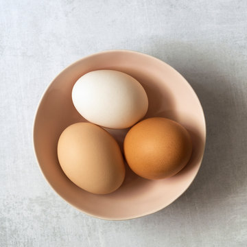Close-up view of three hen eggs in a bowl.