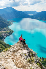 Via ferrata female climber enjoying the views over lake Attersee, Austria, with blue waters, in a bright, hot, Summer day. Perfect Summer destination for rock and water activities.