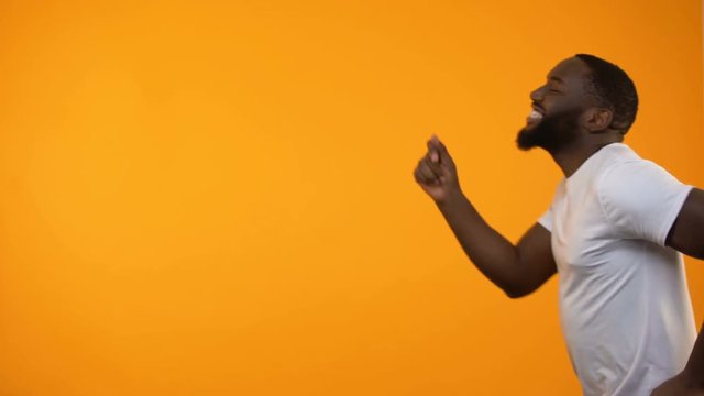 Joyful man moving back and forth against yellow background, having fun, close-up