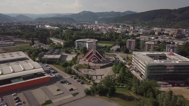 Drone shot of a modern catholic church near some gardens in Zilina, Slovakia, sorrounded by hills