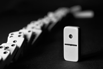 row of fallen dominoes, one standing domino