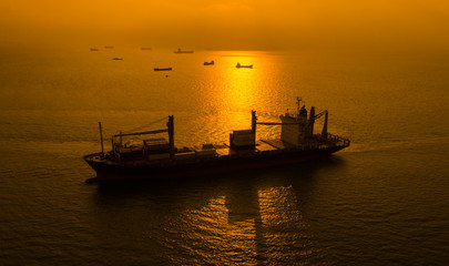 Fototapeta premium silhouette shipping cargo containers on the sea and the sunrise background