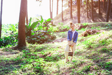 Beautiful Asian woman in the pine wood wearing jean jacket