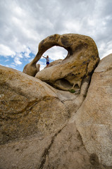 Moibus Arch, also known as the Whitney Portal Arch, in the Alabama Hills area of California. Woman poses inside the natural arch