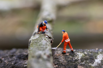 Miniature people: Logger wood cutting for house construction, using image for business concept.