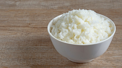 Cooked jasmine rice in white bowl on wooden table with copy space,high calories food,selective focus