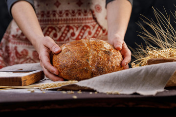 Hands holding round artisan bread. The concept of healthy food and traditional bakery.