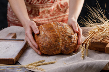 Hands holding round rye bread. The concept of healthy food and traditional bakery.