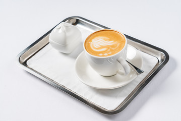 Hot coffee latte cappuccino spiral foam on the silver board