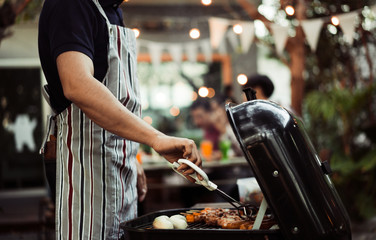 Asian man are cooking for a group of friends to eat barbecue - obrazy, fototapety, plakaty