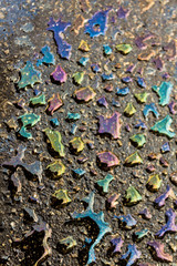 Abstract rainbow reflection on oil stains above asphalt road floor background.