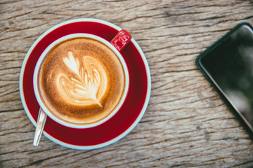 A cup of hot latte coffee,mobile smart phone,workplace,vintage style.