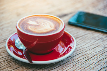 A cup of hot latte coffee,mobile smart phone,workplace,vintage style.