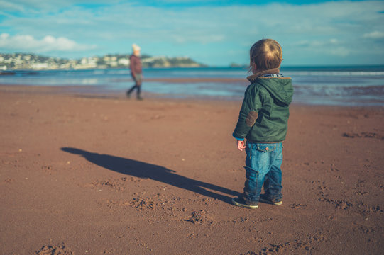 Little toddler standing on the beach in winter