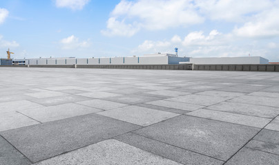 Empty square floor tiles and modern factory buildings and warehouses..