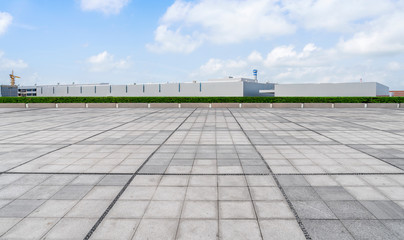 Empty square floor tiles and modern factory buildings and warehouses..