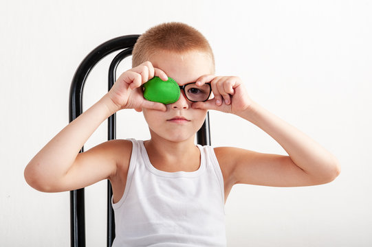 Child in glases with green Occluder. Ortopad Boys Eye Patces nozzle for glasses for treating strabismus (lazy eye).Nine years old boy with one eye covered by eye pad and with eye glasses.