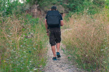 Man hiking with black backpack in summer