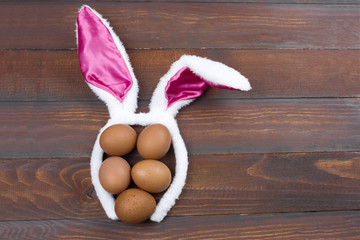top view brown eggs with bunny ears on a wooden background