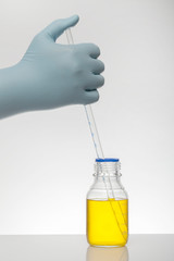 A hand in laboratory gloves mixes chemistry. Liquid in laboratory bottles. Scientific biochemical...