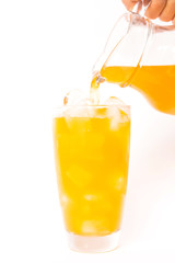 Summer drink: pouring fresh orange juice on ice in glass isolated on white background