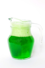 Glass jug of soft drink green soda with dancing bubbles isolated on white background