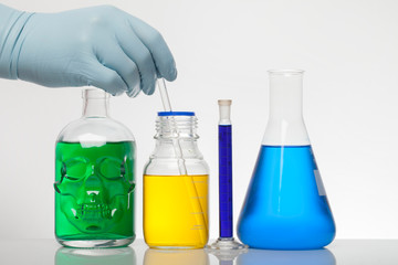 A hand in laboratory gloves mixes chemistry. Liquid in laboratory bottles. Scientific biochemical...