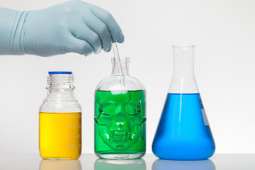 A hand in laboratory gloves mixes chemistry. Liquid in laboratory bottles. Scientific biochemical...