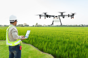 Fototapeta na wymiar Technician farmer use wifi computer control agriculture drone fly to sprayed fertilizer on the rice fields, Smart farm 4.0 concept