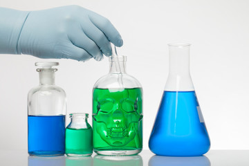 A hand in laboratory gloves mixes chemistry. Liquid in laboratory bottles. Scientific biochemical laboratory. Colorful liquid.