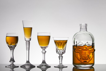 A skull bottle and crystal glasses with a liquid, alcohol drink.