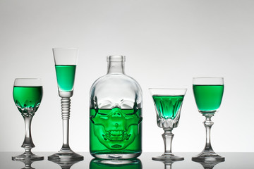 A skull bottle and crystal glasses with a liquid, alcohol drink.