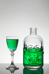 A skull bottle and crystal glasses with a liquid, alcohol drink.