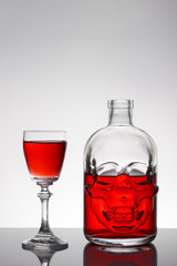 A skull bottle and crystal glasses with a liquid, alcohol drink.