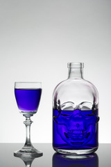 A skull bottle and crystal glasses with a liquid, alcohol drink.