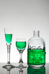 A skull bottle and crystal glasses with a liquid, alcohol drink.