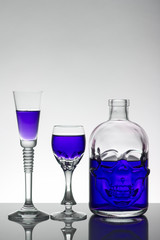 A skull bottle and crystal glasses with a liquid, alcohol drink.
