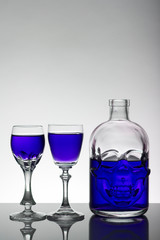 A skull bottle and crystal glasses with a liquid, alcohol drink.