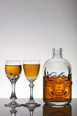 Naklejka na ściany i meble A skull bottle and crystal glasses with a liquid, alcohol drink.