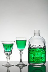 A skull bottle and crystal glasses with a liquid, alcohol drink.