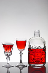 A skull bottle and crystal glasses with a liquid, alcohol drink.