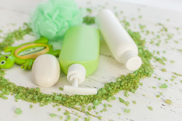 Shampoo bottles on wooden backround. Baby bath accessories. Child toilet stuff. Bathroom tubes, balm, sea salt, soap.