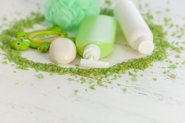 Shampoo bottles on wooden backround. Baby bath accessories. Child toilet stuff. Bathroom tubes, balm, sea salt, soap.