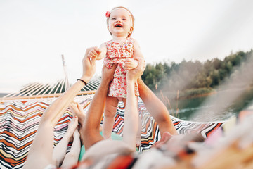 happy stylish family playing with joyful daughter and cuddling, relaxing in hammock on summer...