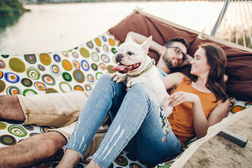 Cute dog smiling while on a trip with his owners, joyful young family, man and woman lying in...