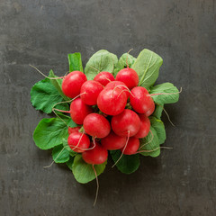 A bunch of radishes on a black stone. Creative layout. Concept-healthy food, vegetarianism, raw food.