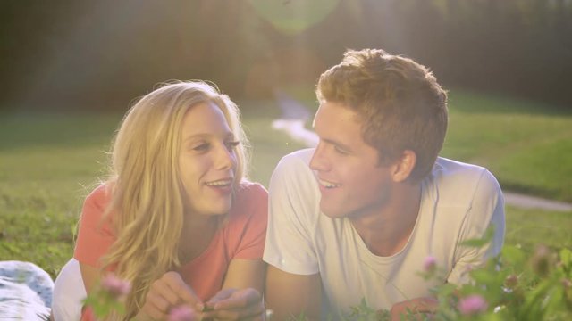 PORTRAIT, LENS FLARE: Cheerful Caucasian couple films a v-log in the idyllic sunny nature. Happy brother and sister filming a video blog for the social media profile. Students video calling home.