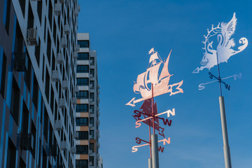 Iron Weathervanes in the Background of the Blue Sky and a New Building