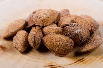 Almonds in shell covered with salt on a wooden background