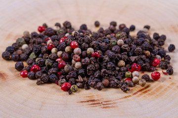 Black, white and red pepper peas on a wooden background